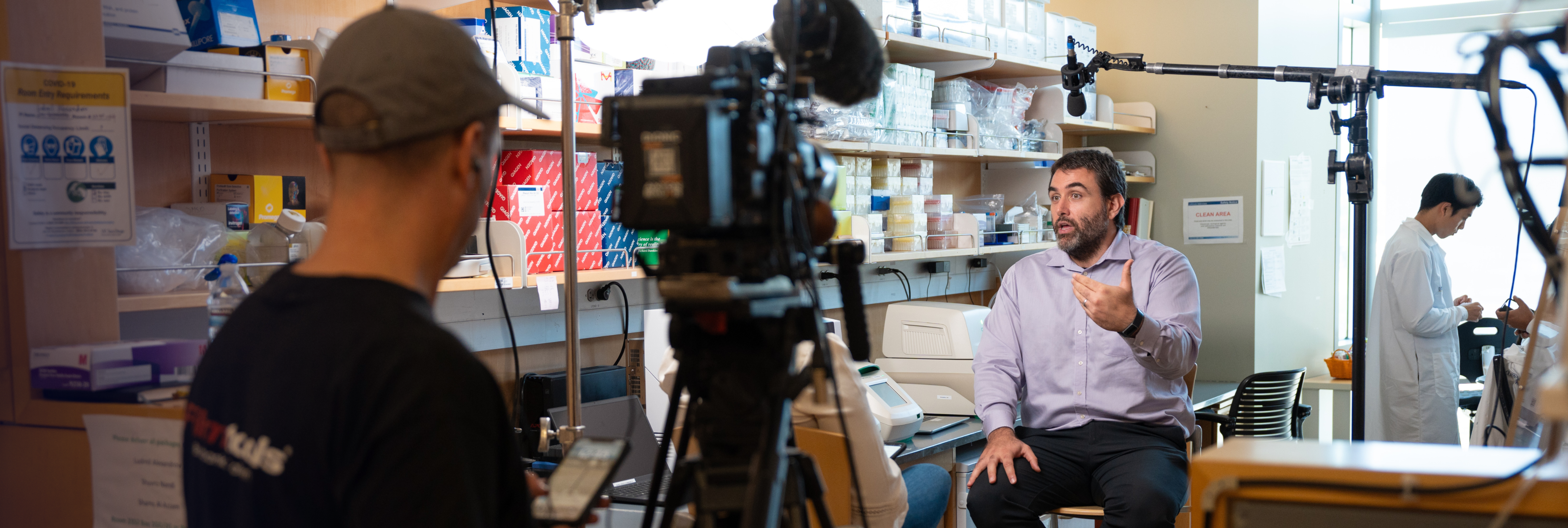 Ludmil Alexandrov speaking to an interviewer in a lab